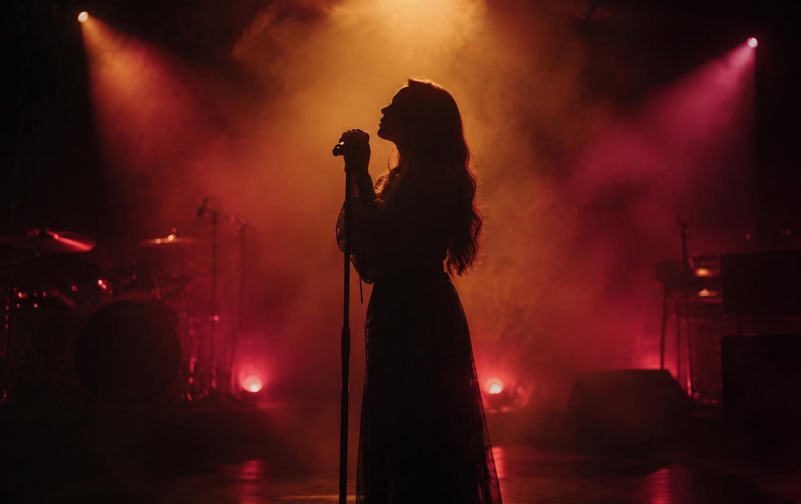 Chanteuse en silhouette sur une scène éclairée en ambre et magenta